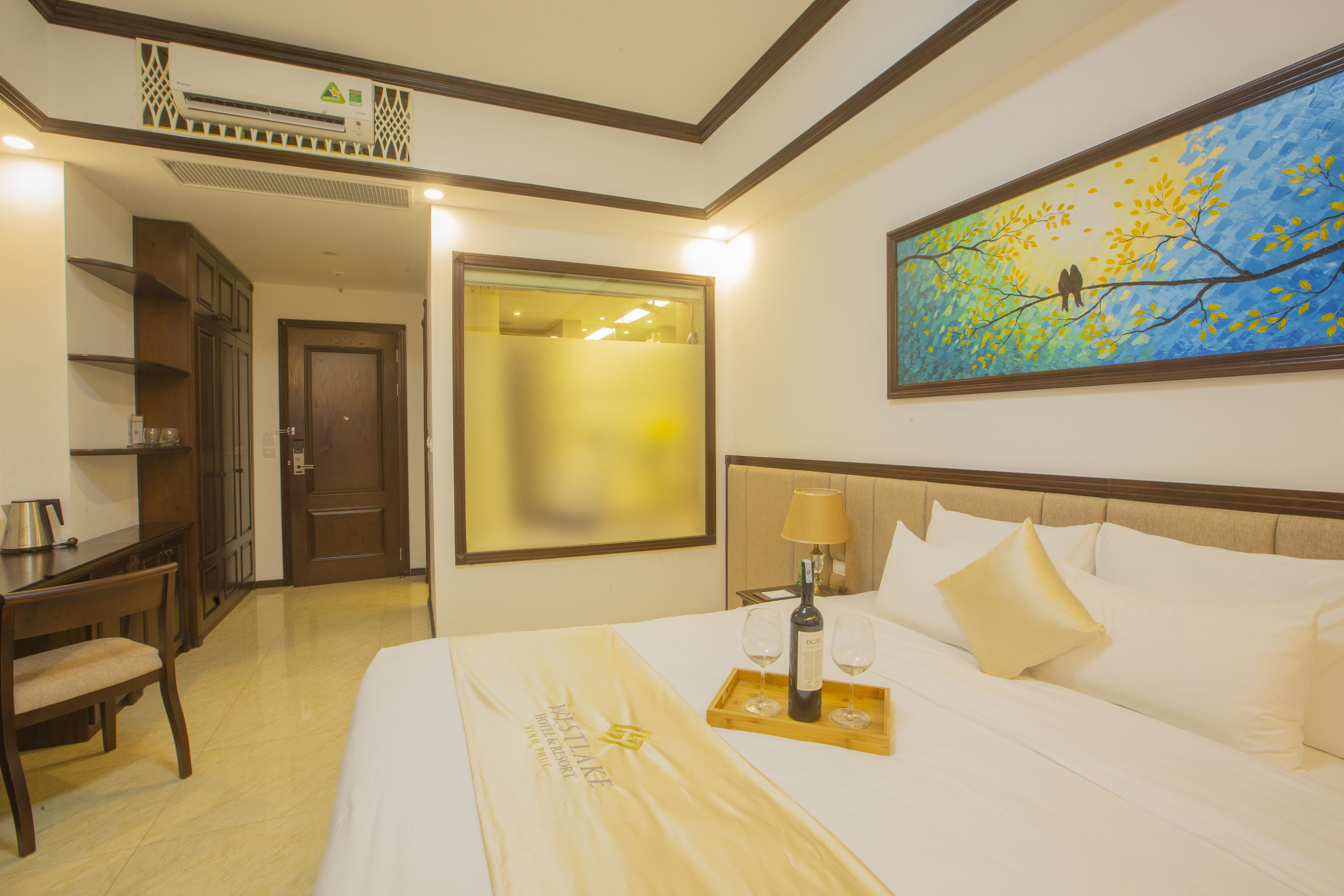 A hotel room with a bed, a desk, a chair, a painting, and a window.