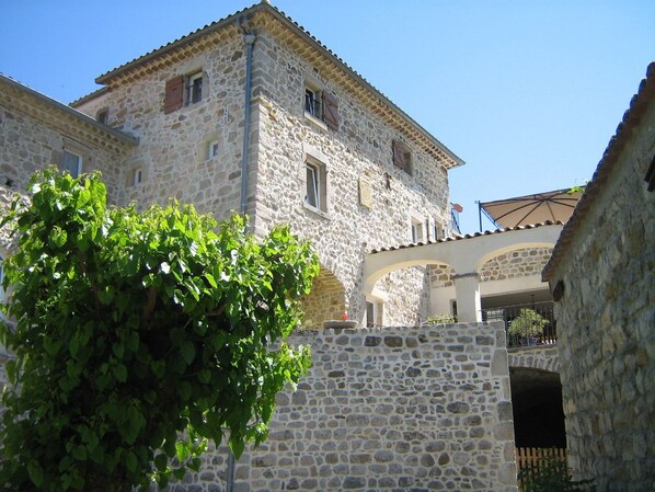 Un edificio de piedra con un balcón y un árbol frente a él.
