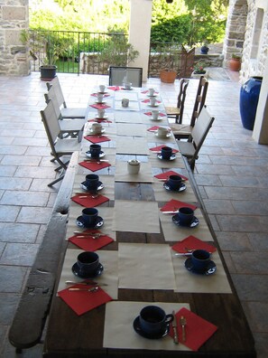 Una larga mesa de comedor dispuesta con varias sillas, lista para una comida.