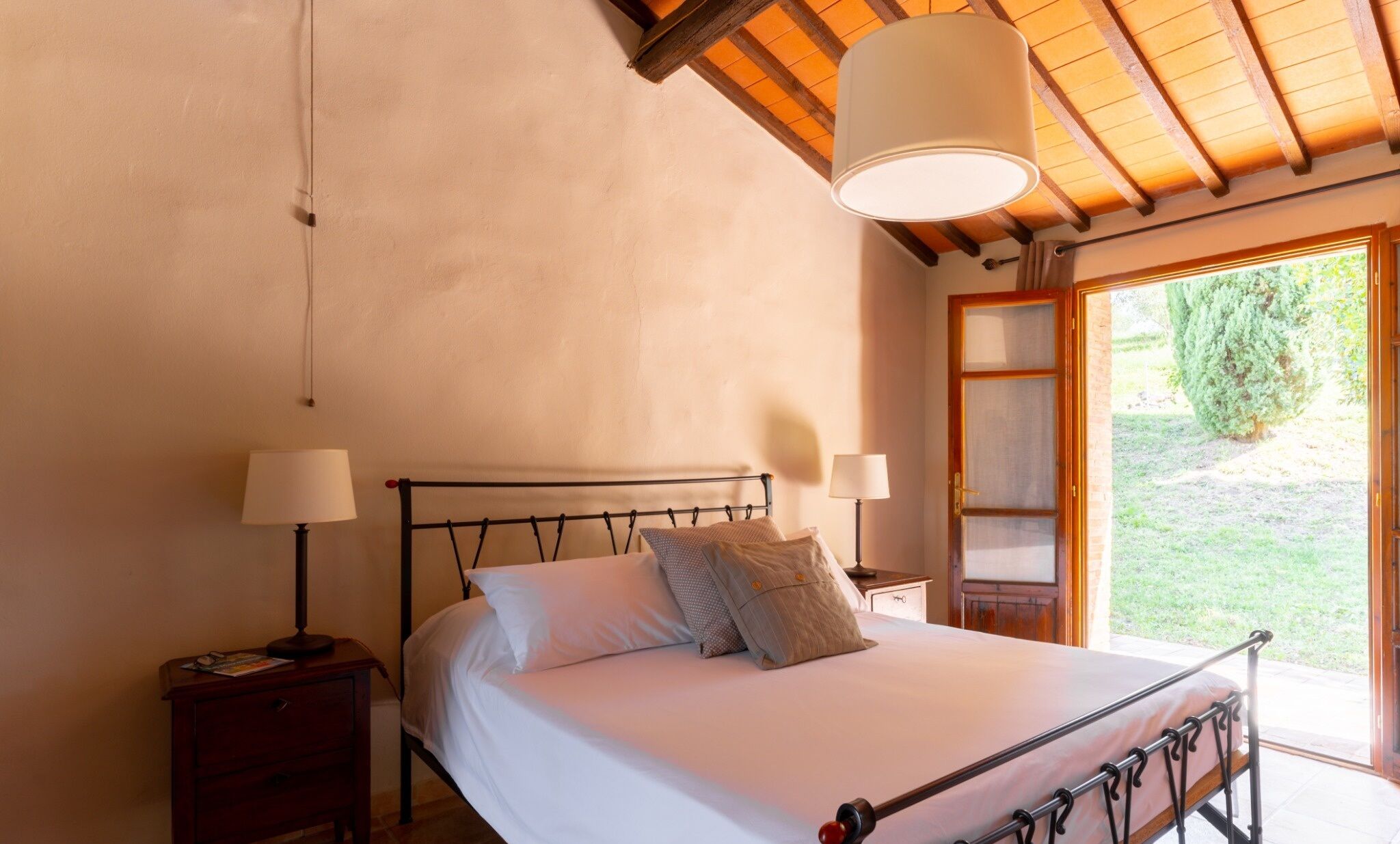 Une chambre à coucher avec un lit, des tables de chevet et une fenêtre donnant sur un paysage verdoyant.