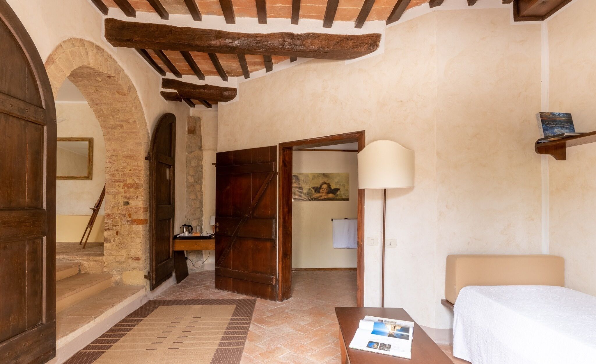 Una habitación con puerta de madera, un cuadro, una lámpara y una cama.