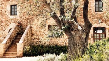 Un edificio in pietra con una targa per la reception, una scala e un albero sullo sfondo.