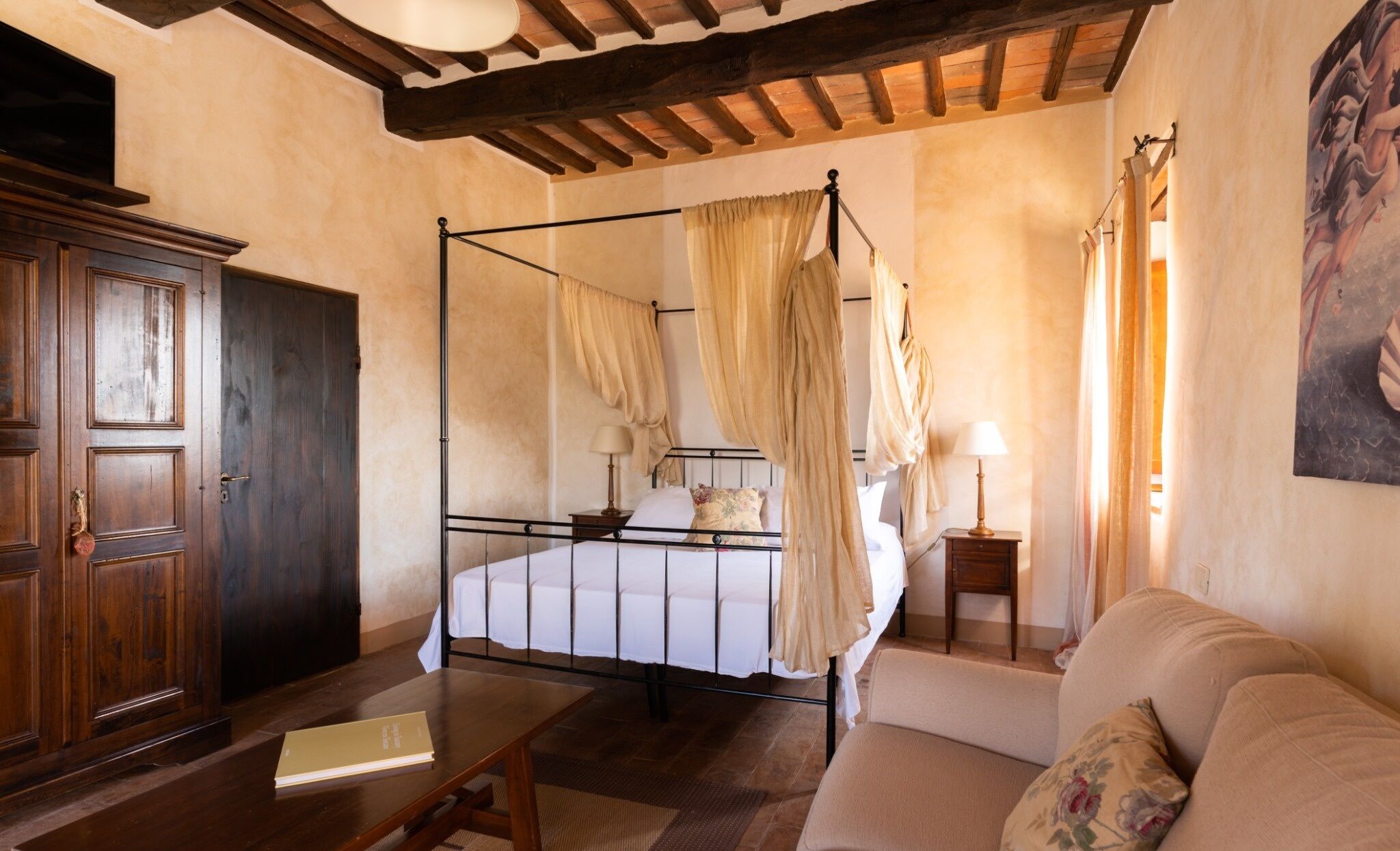 Une chambre à coucher avec un lit à baldaquin, une armoire en bois, une table de chevet avec une lampe et un canapé.