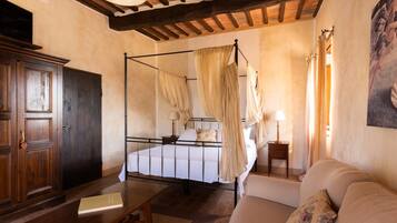 Une chambre à coucher avec un lit à baldaquin, une armoire en bois, une table de chevet avec une lampe et un canapé.