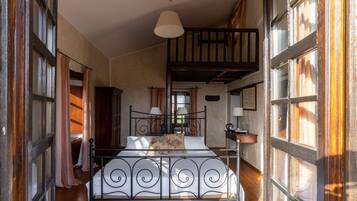 A bedroom with a metal bed frame, a hanging light fixture, and large windows with curtains.