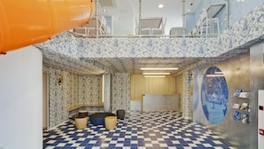 A spacious room with a checkered floor, a large orange slide, and a high ceiling with skylights. - Loop INN Hostel Cartagena (Cartagena)