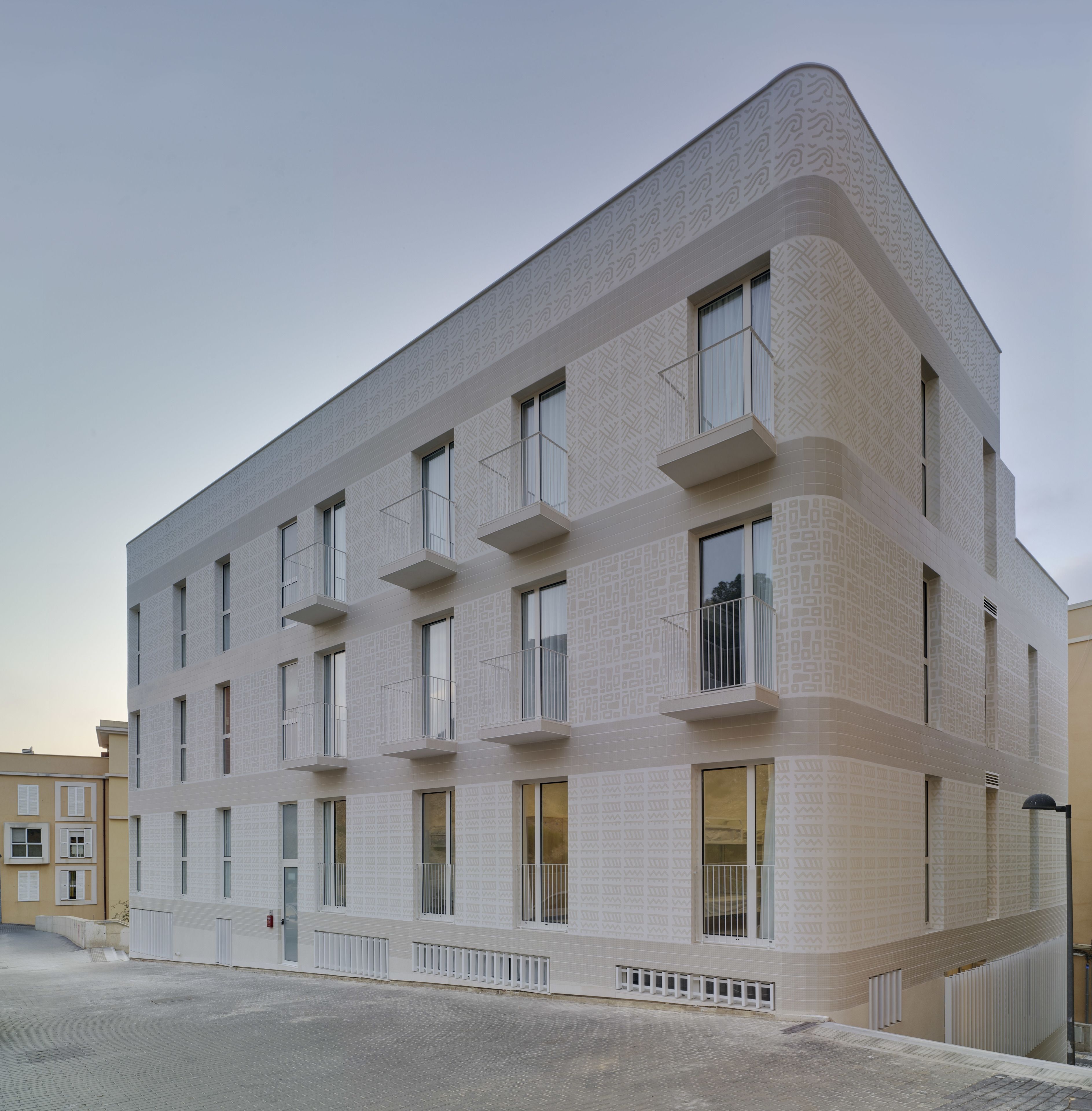 A modern building with a geometric facade, multiple balconies, and large windows.