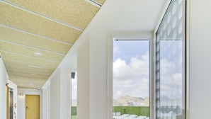 A modern hotel corridor with a large window offering a view of a grassy area and distant hills. - Loop INN Hostel Cartagena (Cartagena)