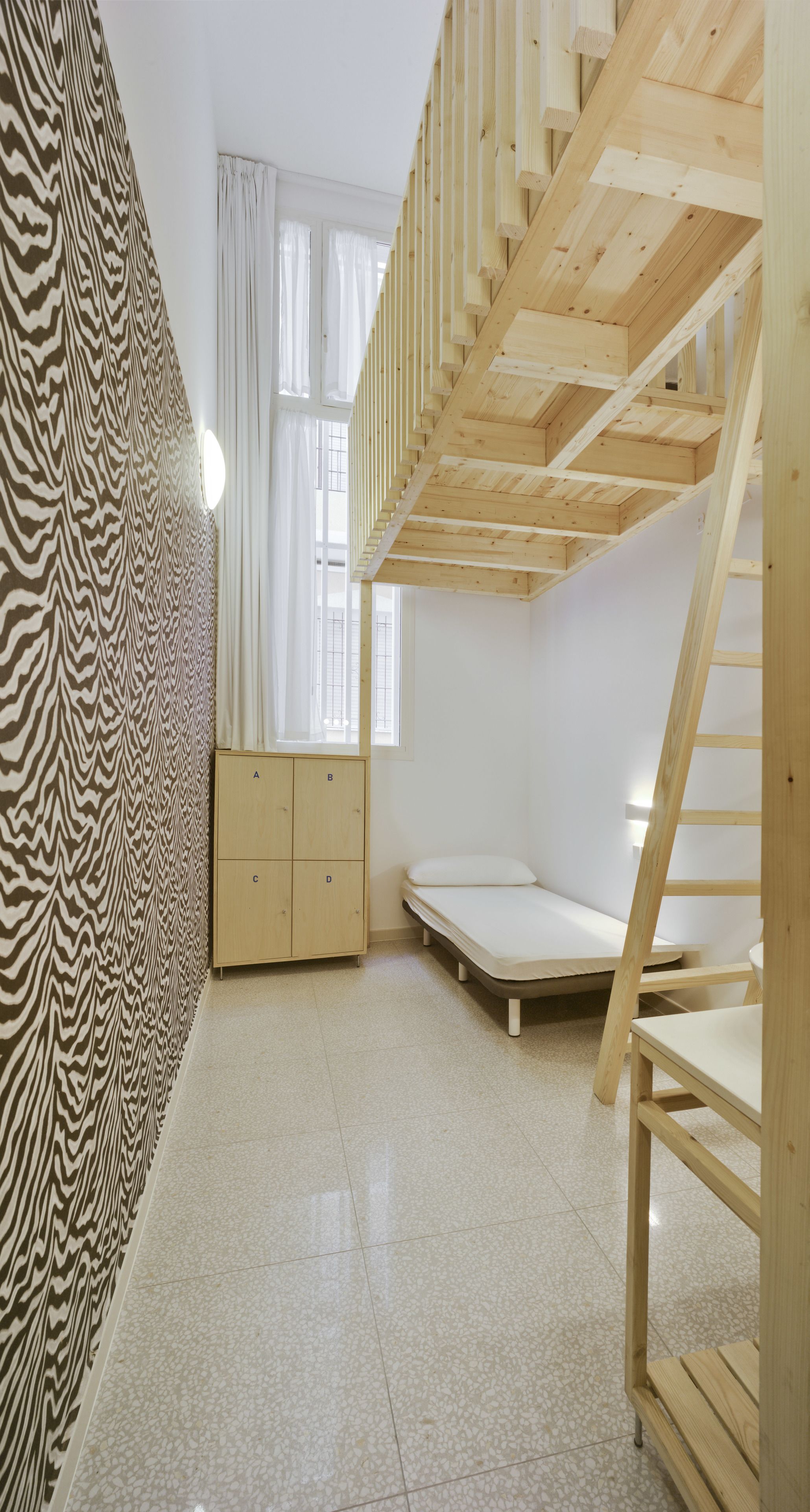 A room with a bunk bed, a wardrobe, and a patterned wall.