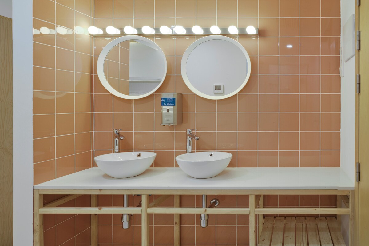 A bathroom with two sinks, mirrors, and overhead lighting.