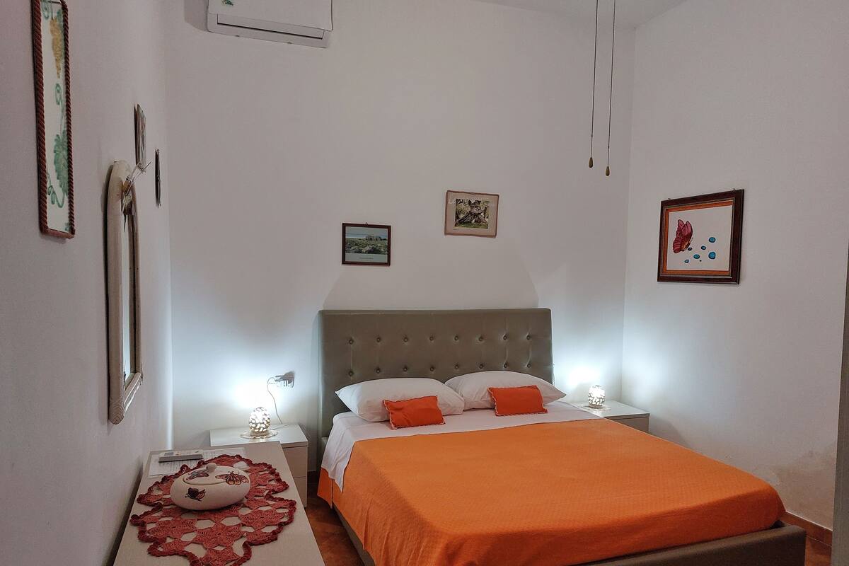 A bedroom with a bed, nightstands, a mirror, and wall art.