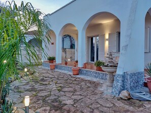 A courtyard with a stone floor, potted plants, and a fountain. - Villa Musella (Porto Cesareo)