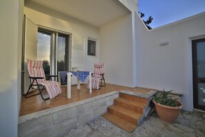 A patio with two striped chairs, a small table, and a potted plant. - Villa Musella (Porto Cesareo)