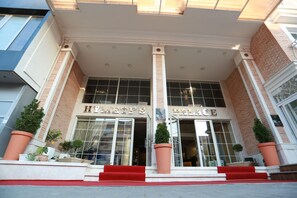 A hotel entrance with a name sign, large windows, and red steps leading up to the door. - Hymetis Palace (Pogradec)