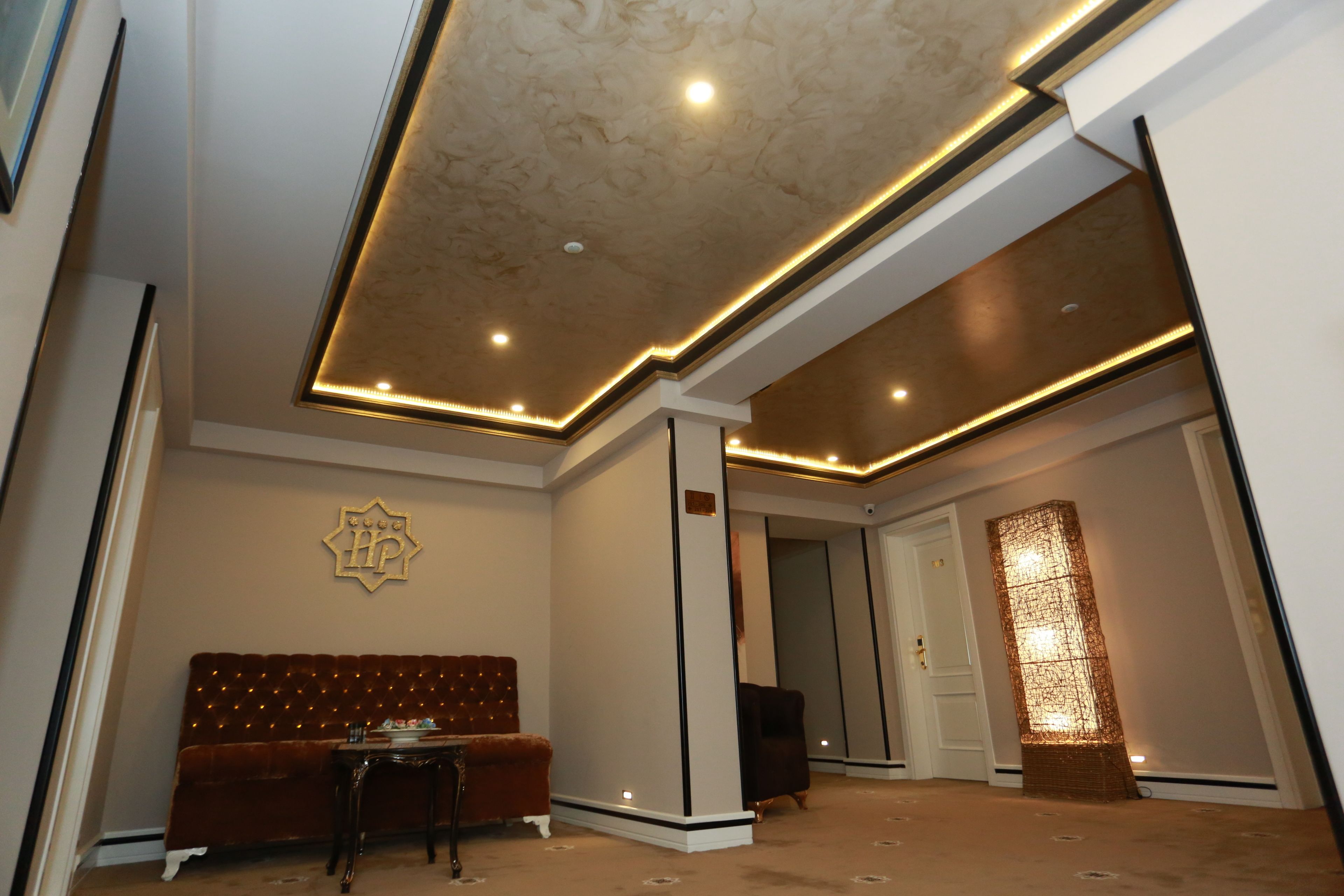 Un hall d’hôtel moderne avec un canapé marron moelleux, une petite table et un élément décoratif mural.