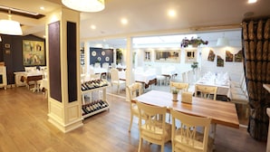 Un restaurante con suelo de madera, mobiliario blanco y una estantería para vinos.