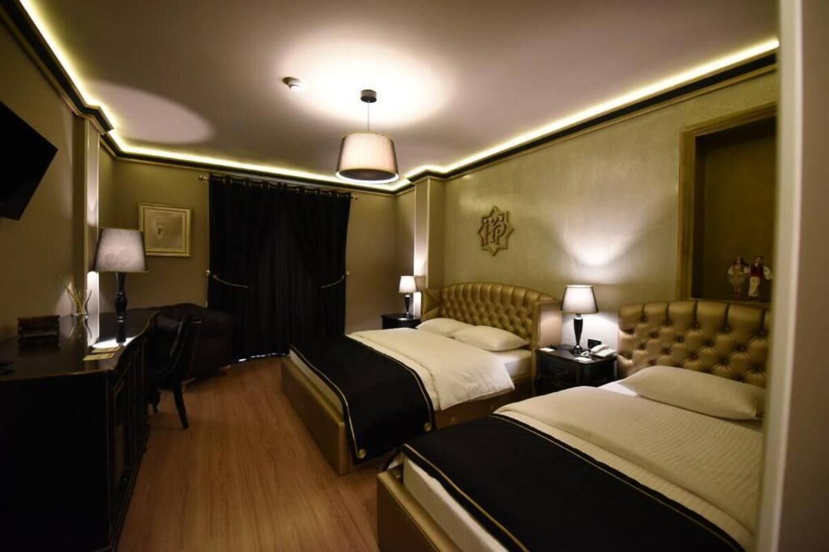 A hotel room with two beds, a desk, and a chair.
