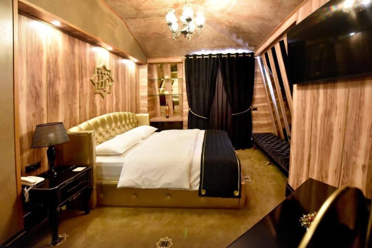 A hotel room with a bed, a desk, a lamp, a TV, and a chandelier.