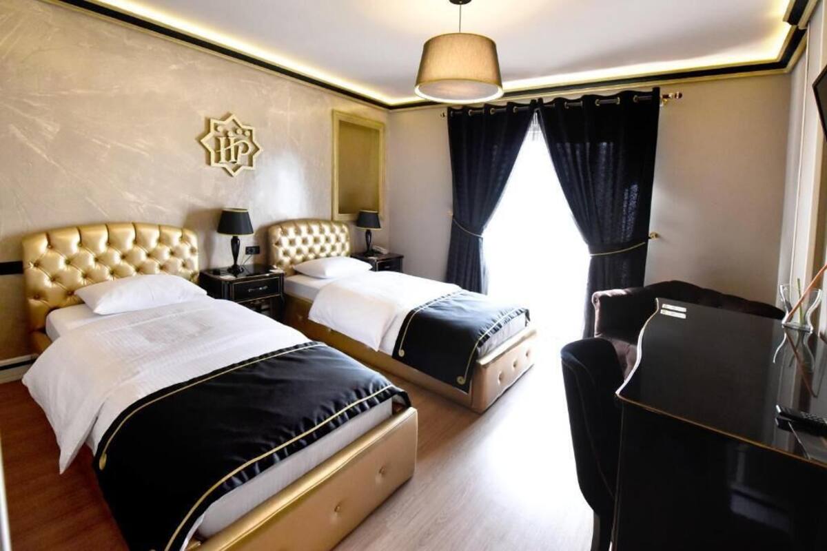 A hotel room with two beds, a desk, and a mirror.