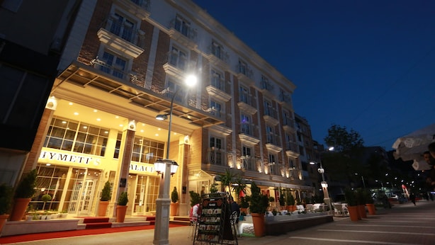 Un hotel con entrada iluminada, zona de estar al aire libre y plantas en macetas.