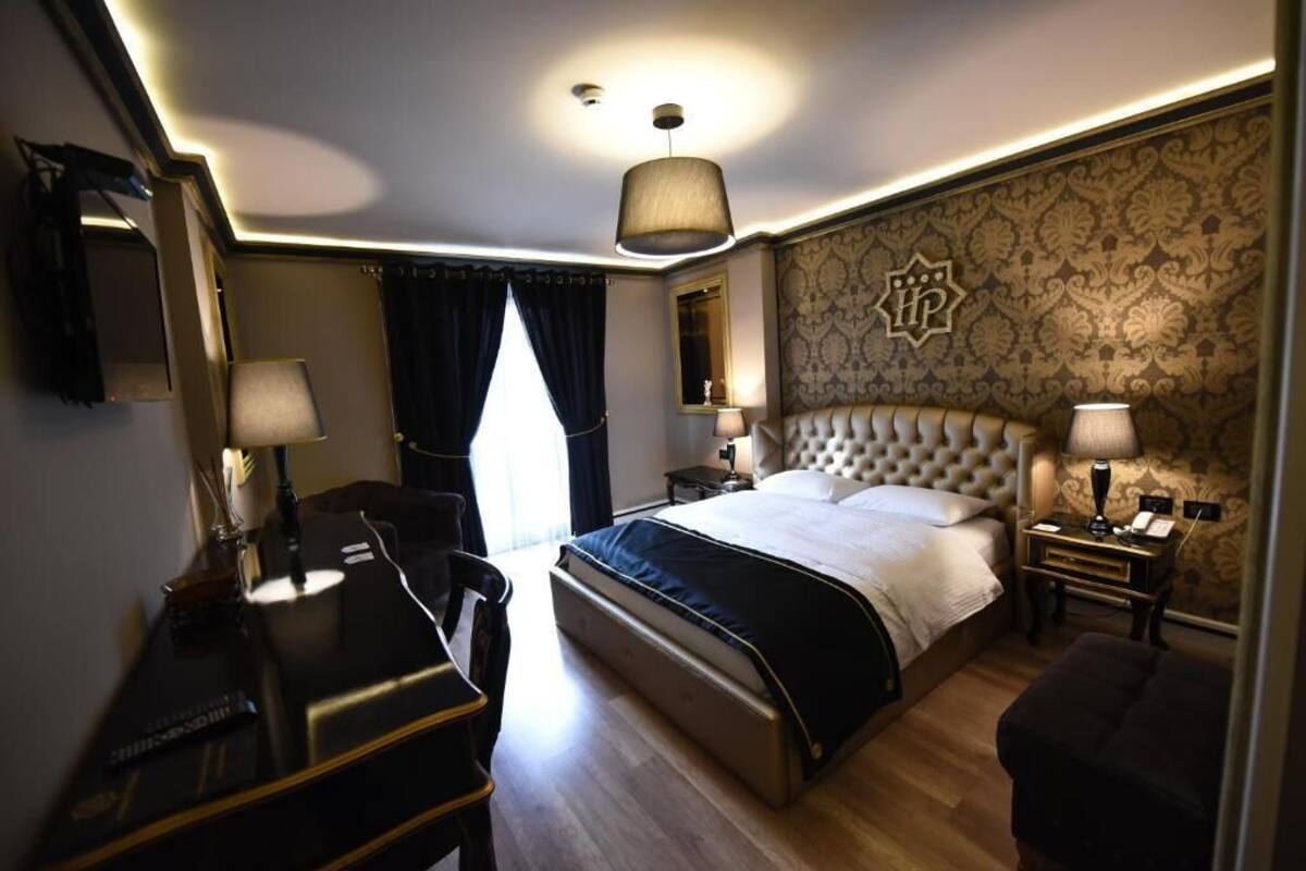 A hotel room with a large bed, a desk, a chair, and a small sofa.