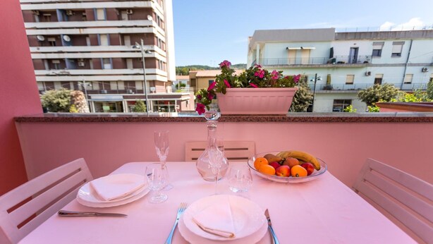 A balcony table set with white plates, cutlery, and a bowl of fruit. -  L'Aurora Viola (Carbonia)
