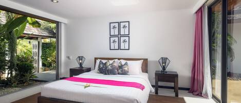 A modern bedroom with a large bed, a view of the outdoors, and a tropical-themed wall art.