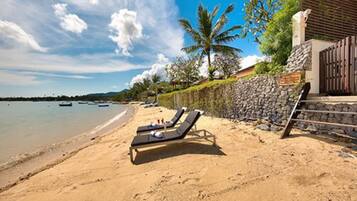 Na praia, espreguiçadeiras, guarda-sóis, toalhas de praia