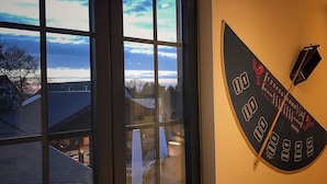A dartboard mounted on a wall with a window in the foreground.