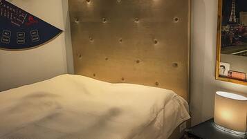 Ein Schlafzimmer mit einem karabinierten Kopfteil, einem Bett mit weißer Bettwäsche, einem roten Teppich, einem an der Wand montierten Roulette-Rad und einem Bilderrahmen mit Stadtansicht.