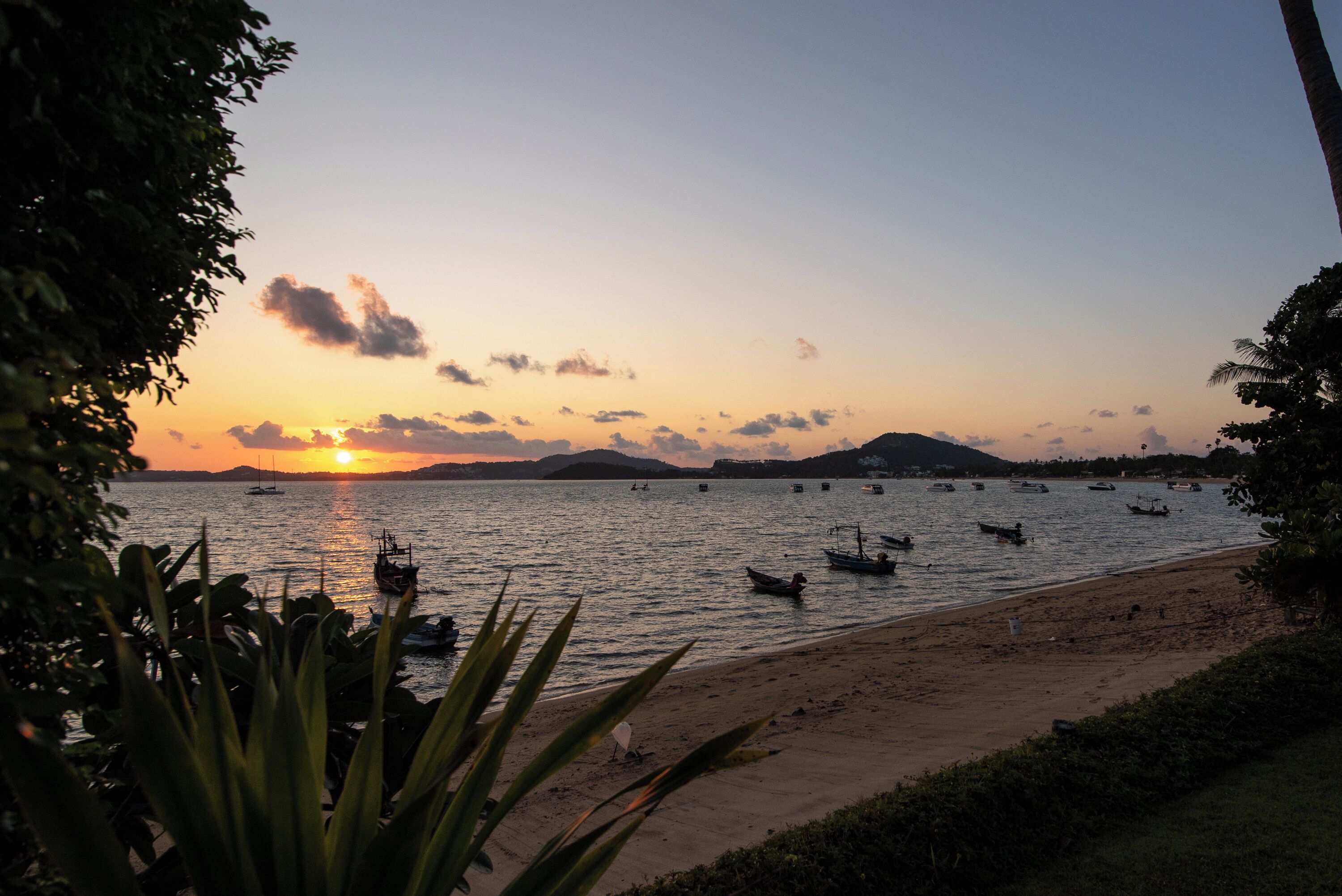 A beach with boats and a sunset.