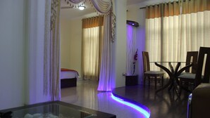 A hotel room with a glass-top dining table, a sofa, and curtains. - Hotel Gokul Residency (New Delhi)