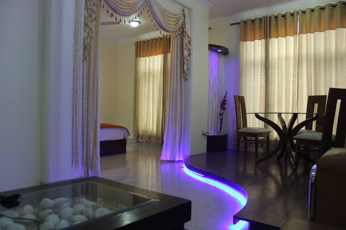 A hotel room with a glass-top dining table, a sofa, and curtains.