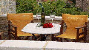 Una mesa con sillas en un balcón con vistas a un pueblo histórico y una torre destacada.