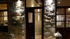 Fachada de piedra con puerta de madera, un letrero de recepción y felpudo para el Hotel Boutique TRAPELA.