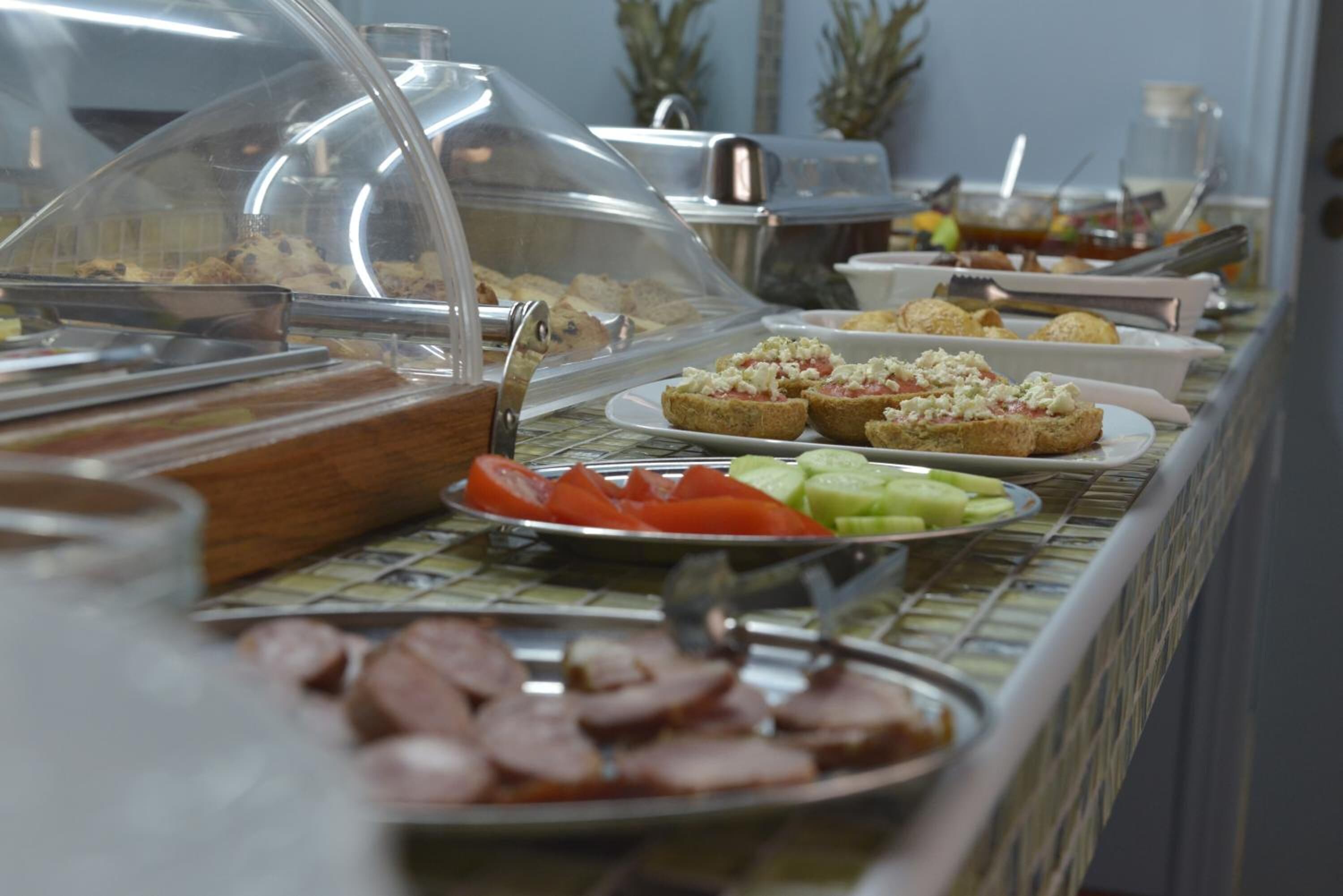 Un bufé con diversos alimentos, como carnes en rodajas, verduras y pan.