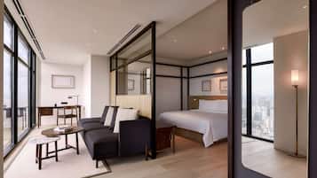 Une chambre d’hôtel moderne, dotée d’un grand lit, d’un canapé, d’une petite table et d’un bureau. Une grande fenêtre offre une vue sur la ville.