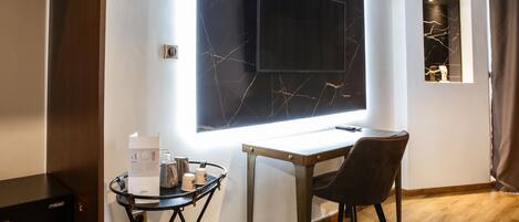 Een moderne kamer met een grote flatscreen televisie aan een marmeren wand, een tafeltje met een dienblad en spullen, een stoel en een houten vloer.