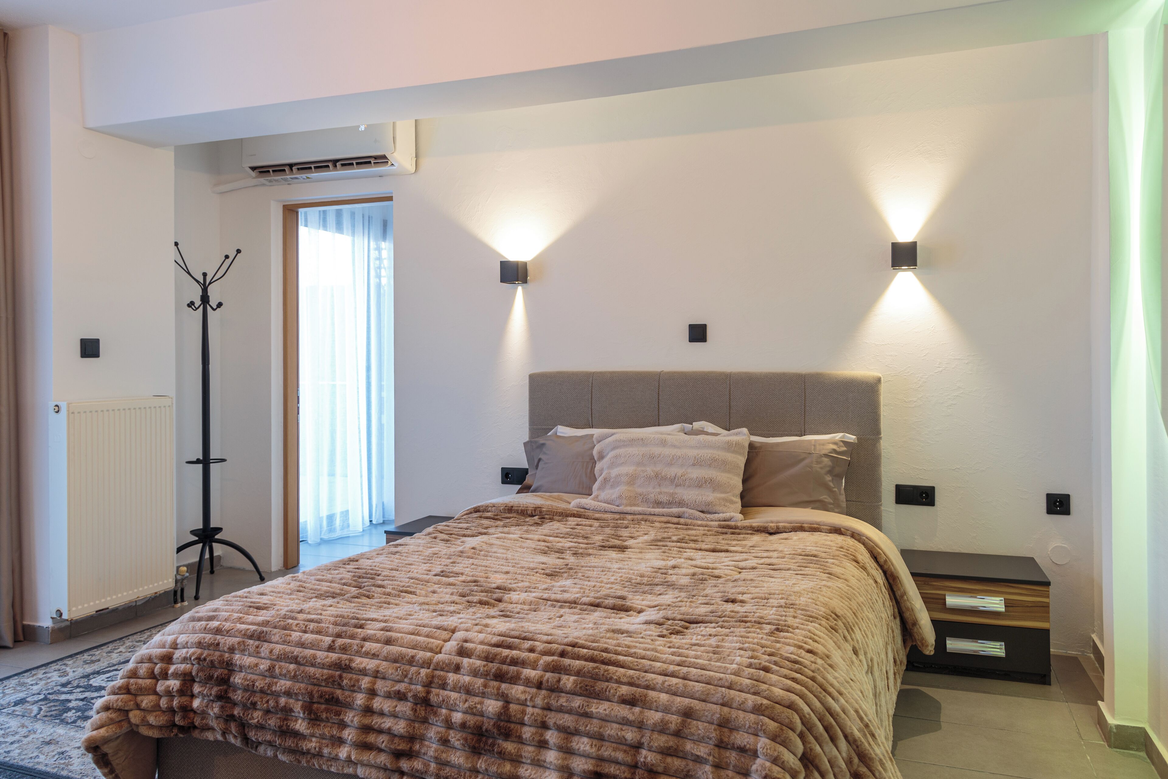 Een slaapkamer met een groot bed, een nachtkastje, een lamp en een radiator.