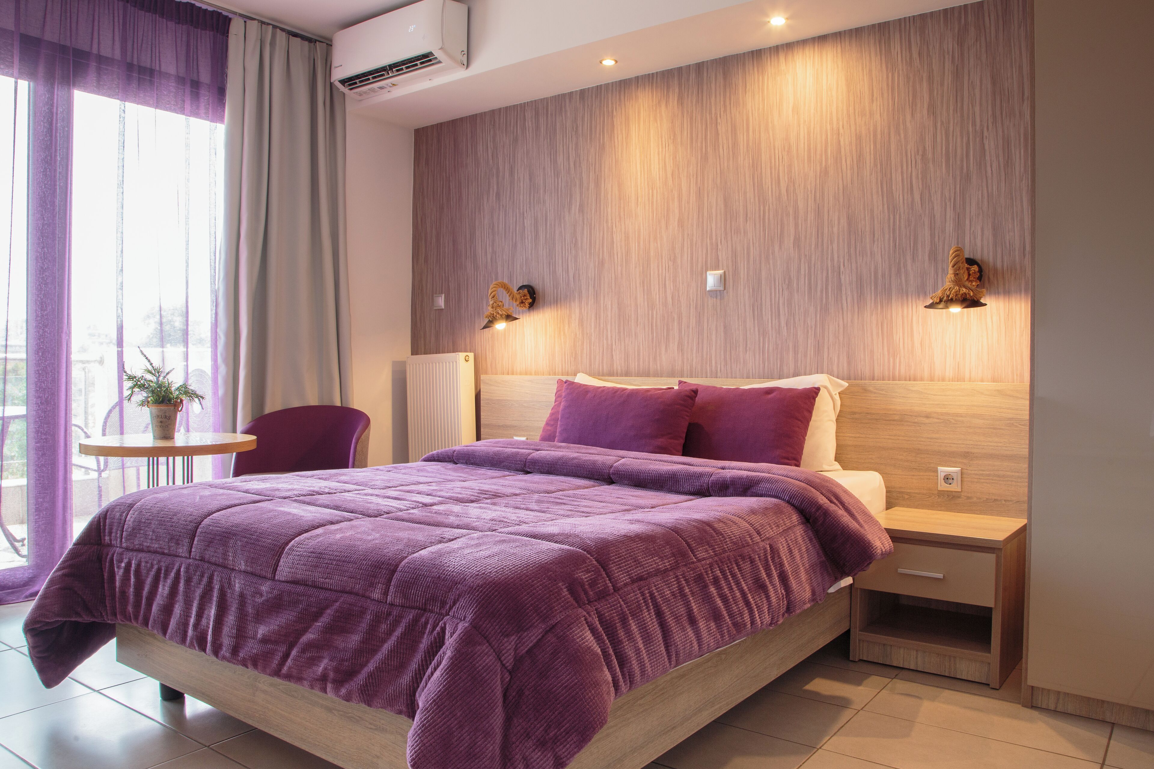 Un dormitorio moderno con una cama grande, una mesita de noche y una pequeña mesa con una planta.