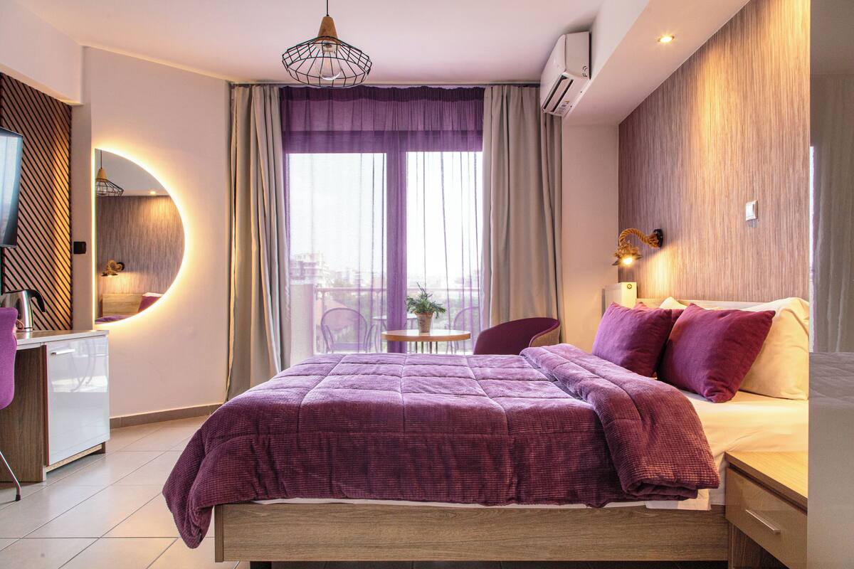 A modern bedroom with a large bed, a desk, and a chair.