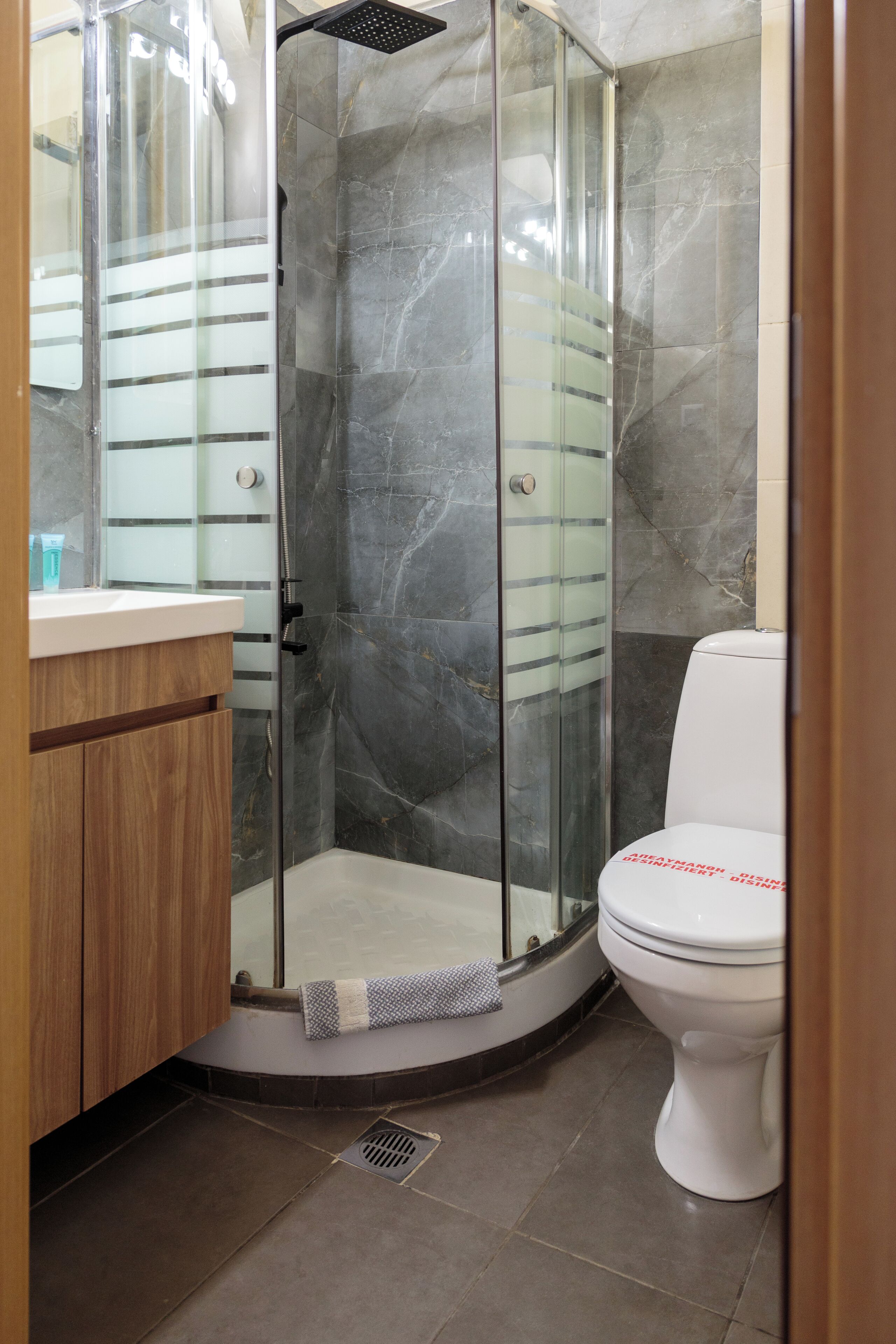 A bathroom with a glass-enclosed shower, a white toilet, and a wooden vanity.