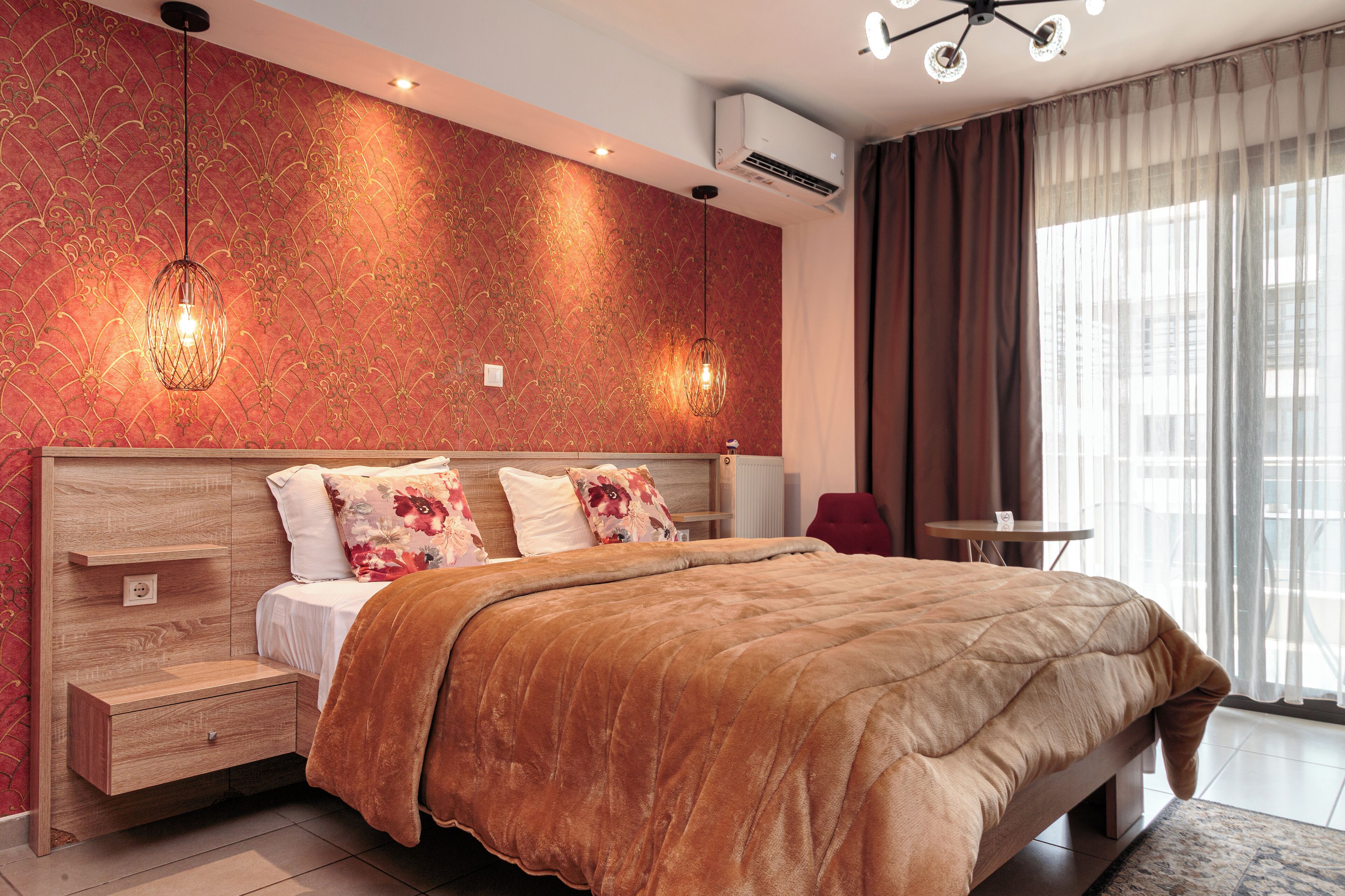 Une chambre d’hôtel moderne avec un grand lit, une tête de lit en bois, des tables de chevet et une petite table ronde.