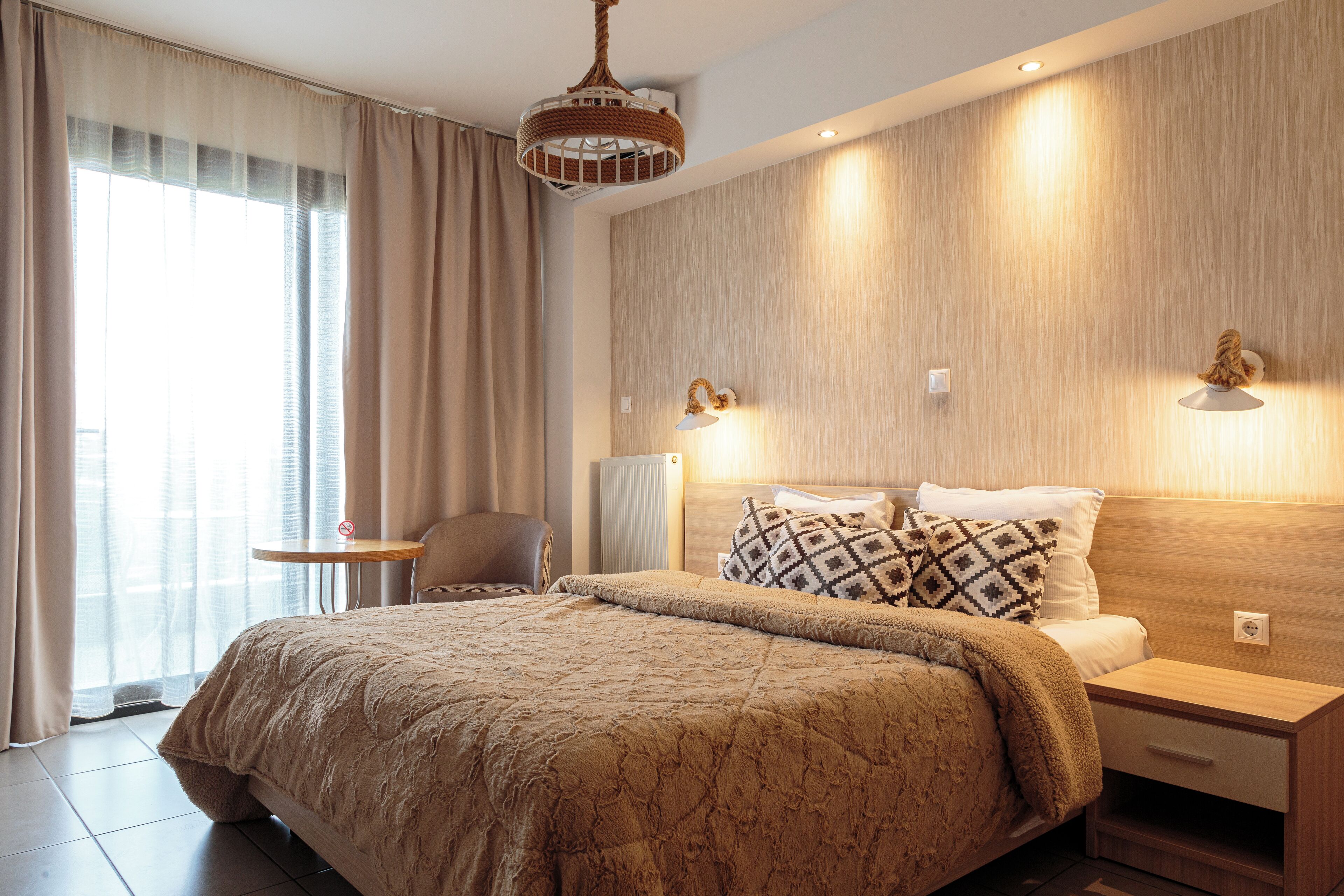 Une chambre d’hôtel moderne avec un grand lit, une table de chevet, une chaise et une petite table.