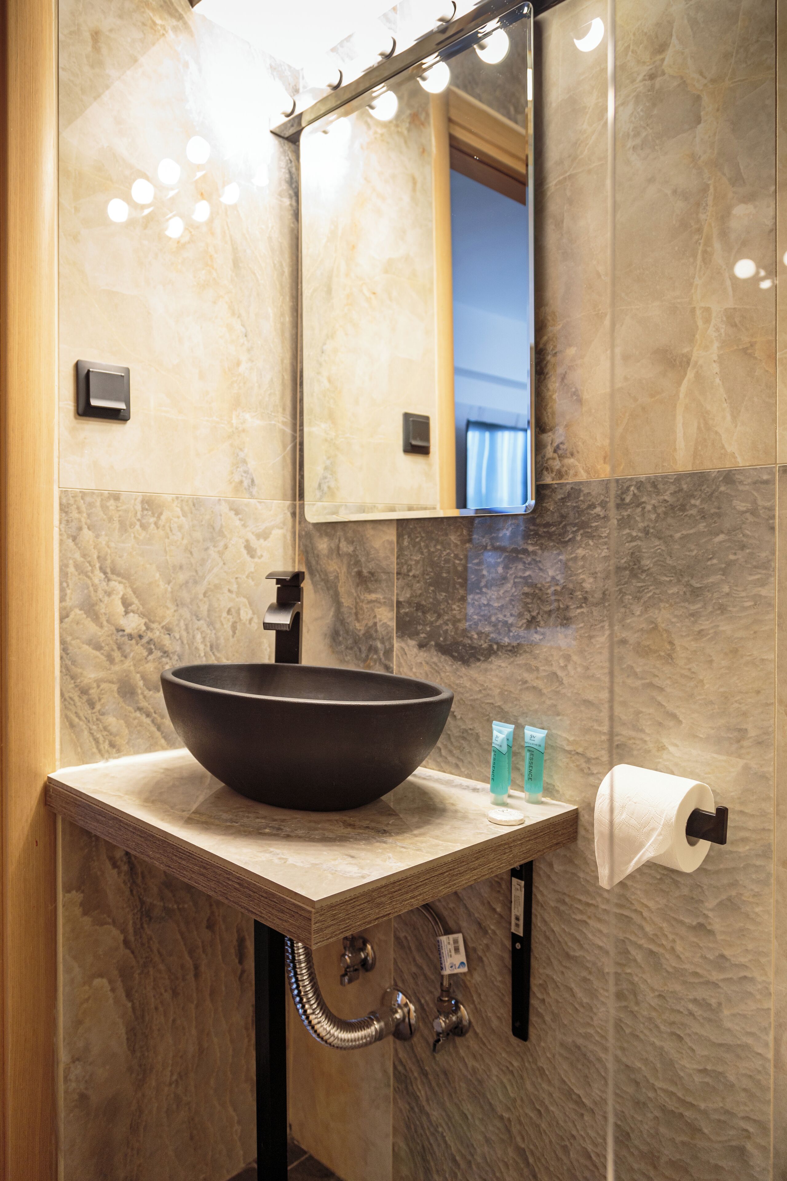 Un baño con un lavabo de pedestal grande, un espejo y un dispensador de toallas.