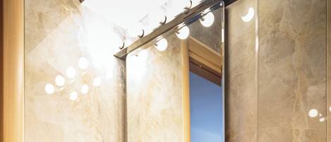 Un baño con un lavabo de pedestal grande, un espejo y un dispensador de toallas.
