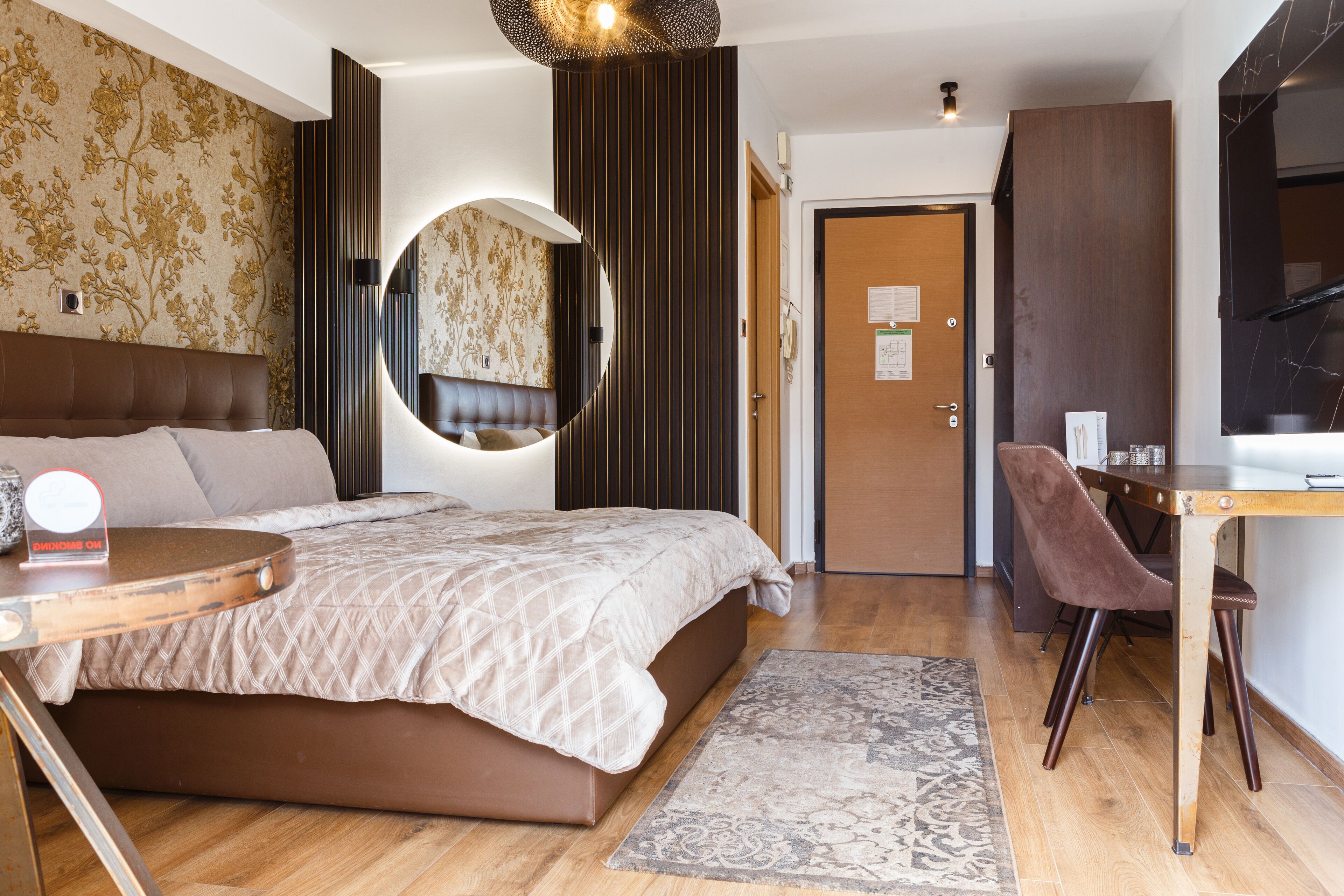 Un dormitorio moderno con una cama grande, un espejo redondo, un escritorio y una silla.