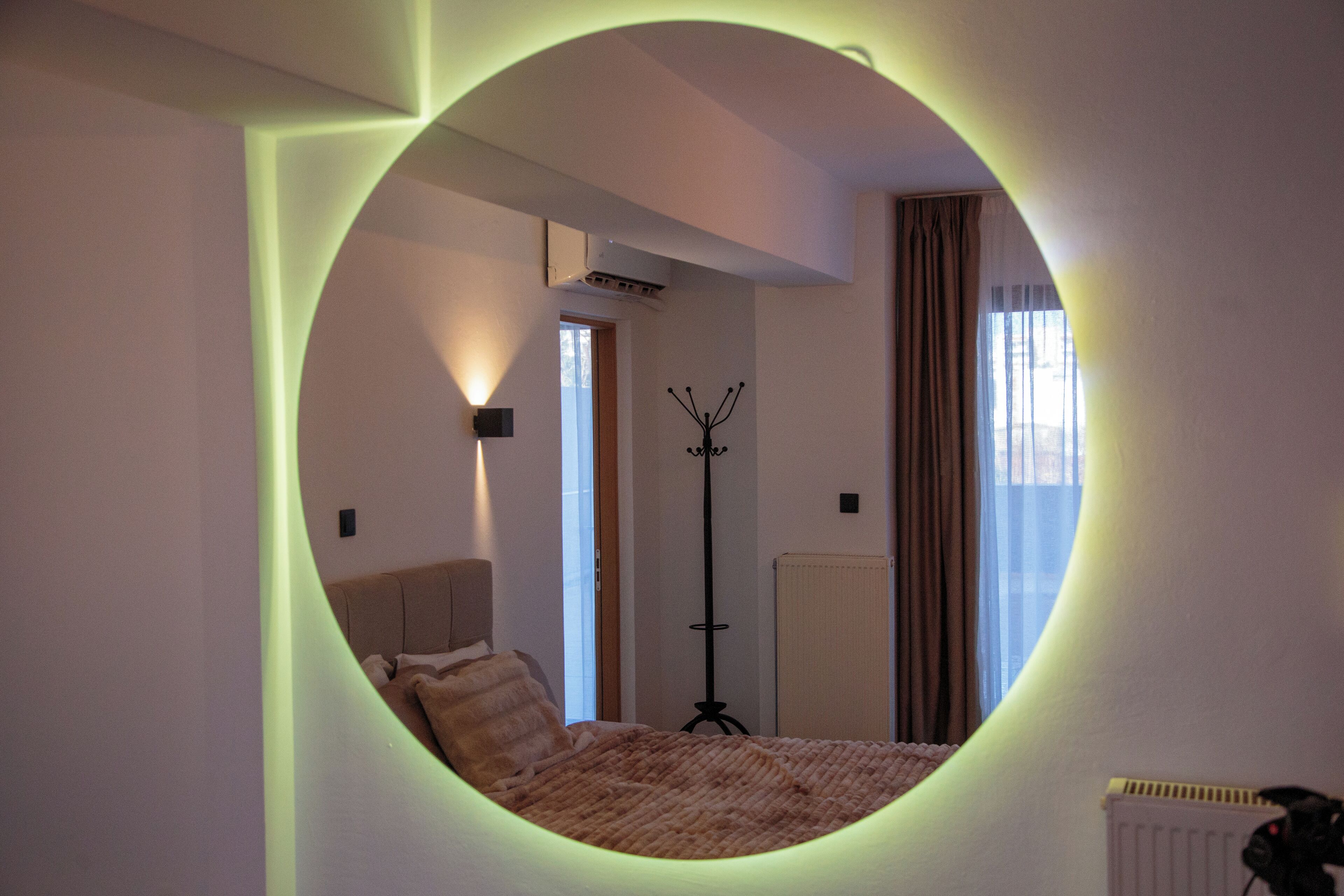 A circular mirror reflecting a bedroom with a bed, a standing lamp, and a radiator.