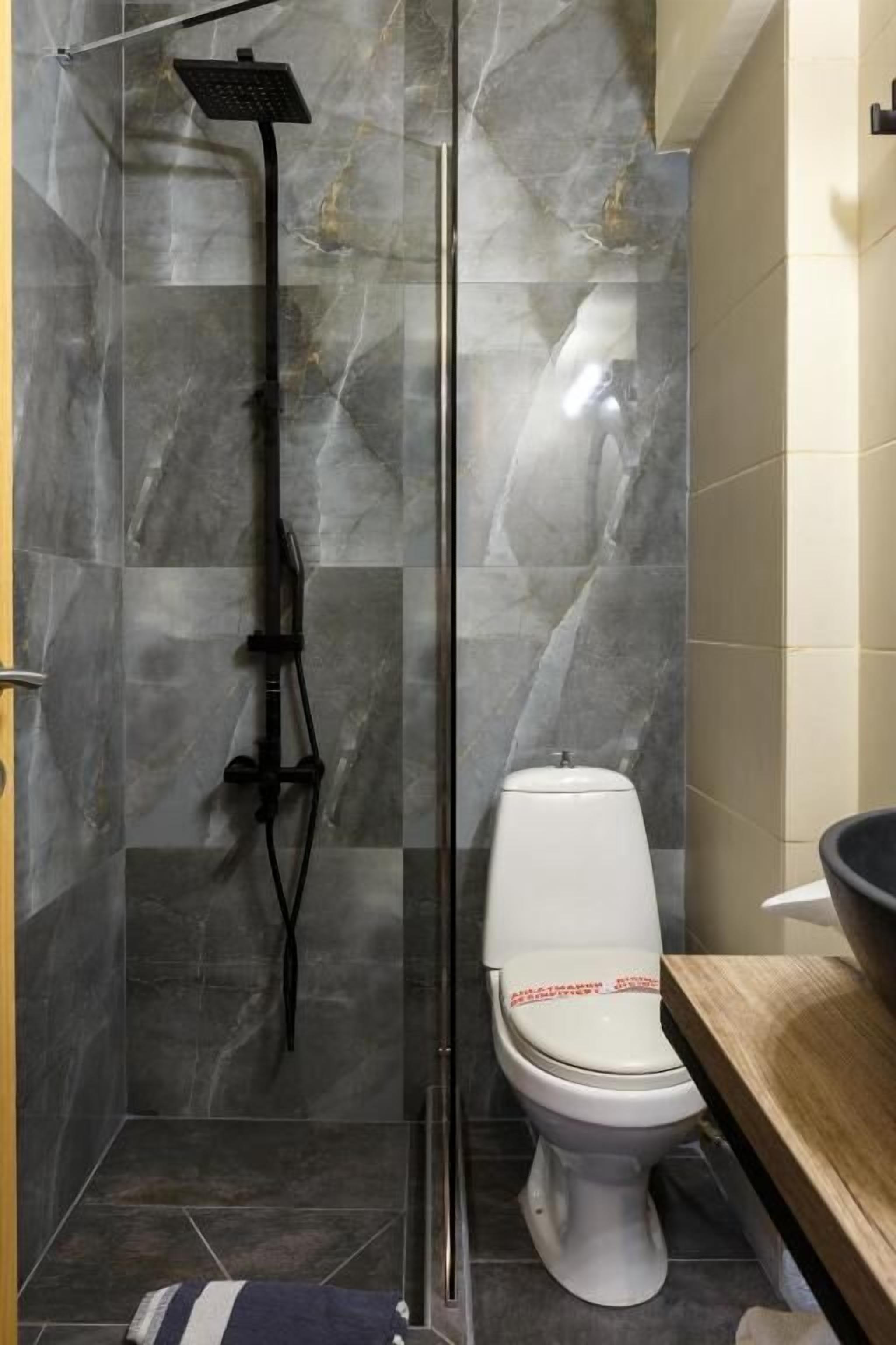 A bathroom with a glass-enclosed shower, a toilet, and a wooden vanity.