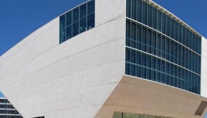 Een modern gebouw met een uniek, hoekig ontwerp, met grote ramen en een combinatie van wit en beige materialen.